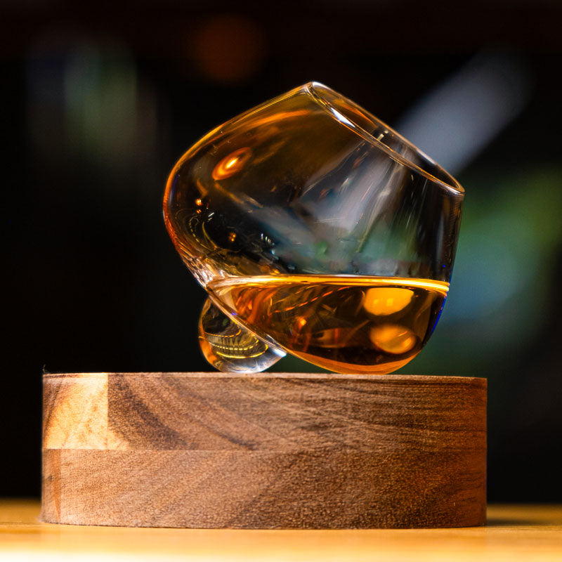 Crystal handcrafted Aequilibrium distillate glass by Audacem on wooden coaster for whiskey, liquors, and spirits